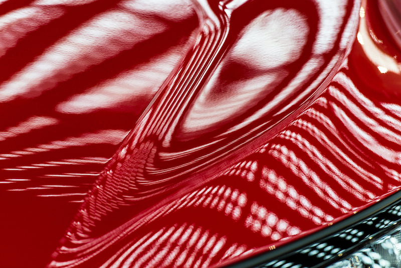 Abstraction of red metal surface of a modern car hood that is shiny due to PPF coating
