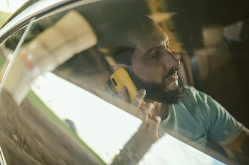 A young man talking on the phone in a car with tinted windows 35%