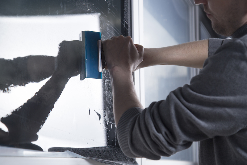 Man installing anti-graffiti window film to business windows