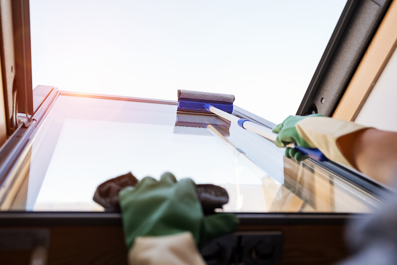 Person cleaning roof light window tints uses a squeegee.