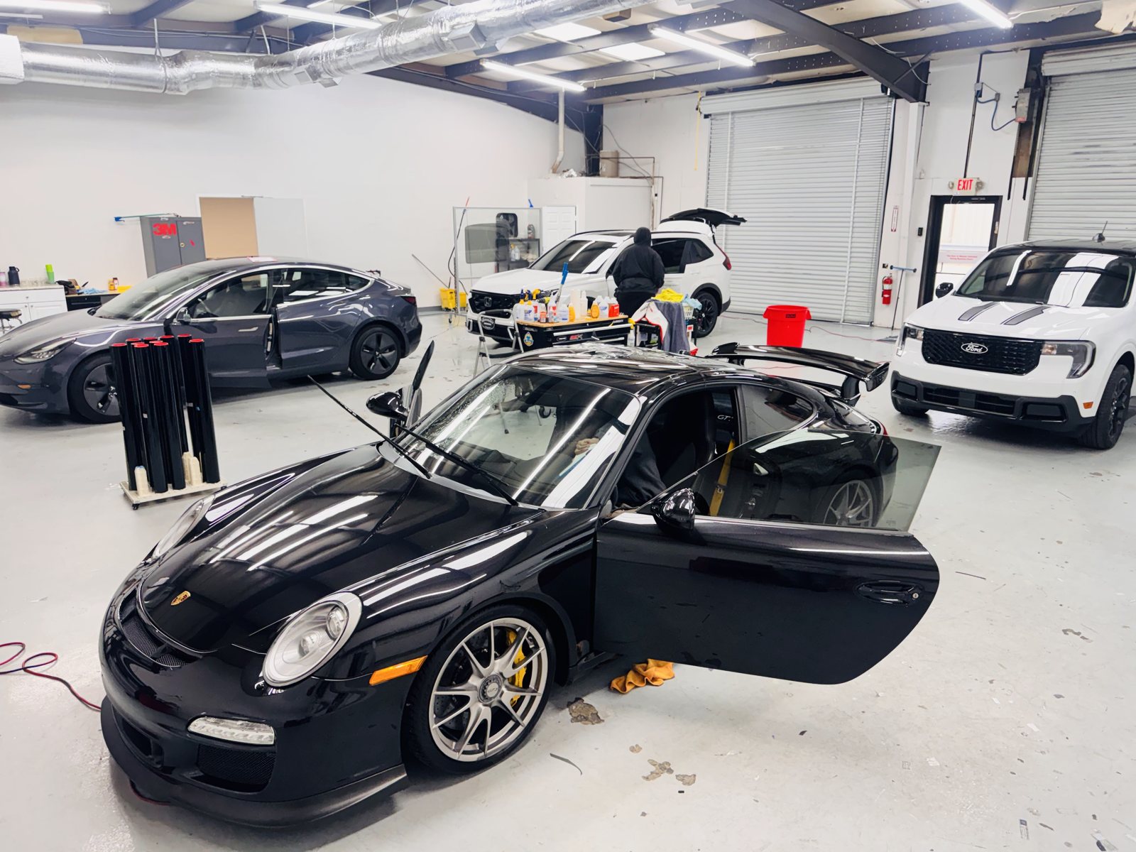 Black Porsche 911 with the doors open for window tint at The Tint Guy
