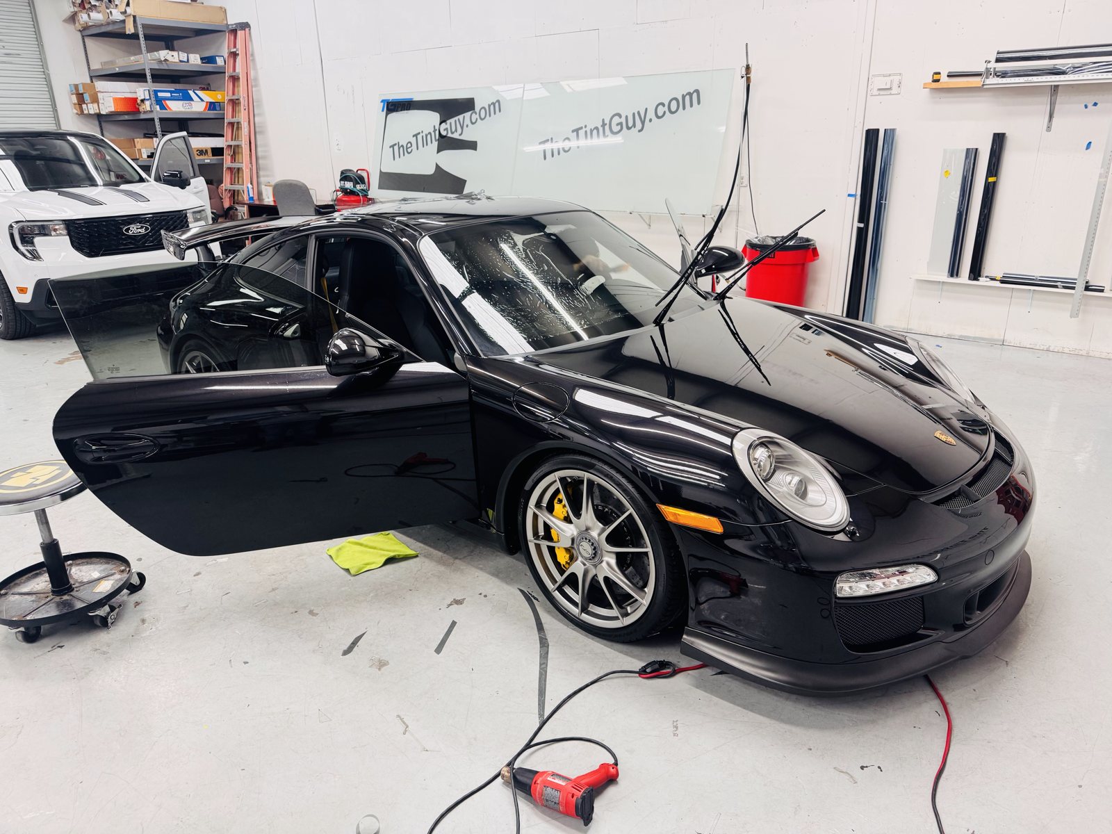 Black Porsche 911 with the doors open inside The Tint Guy shop