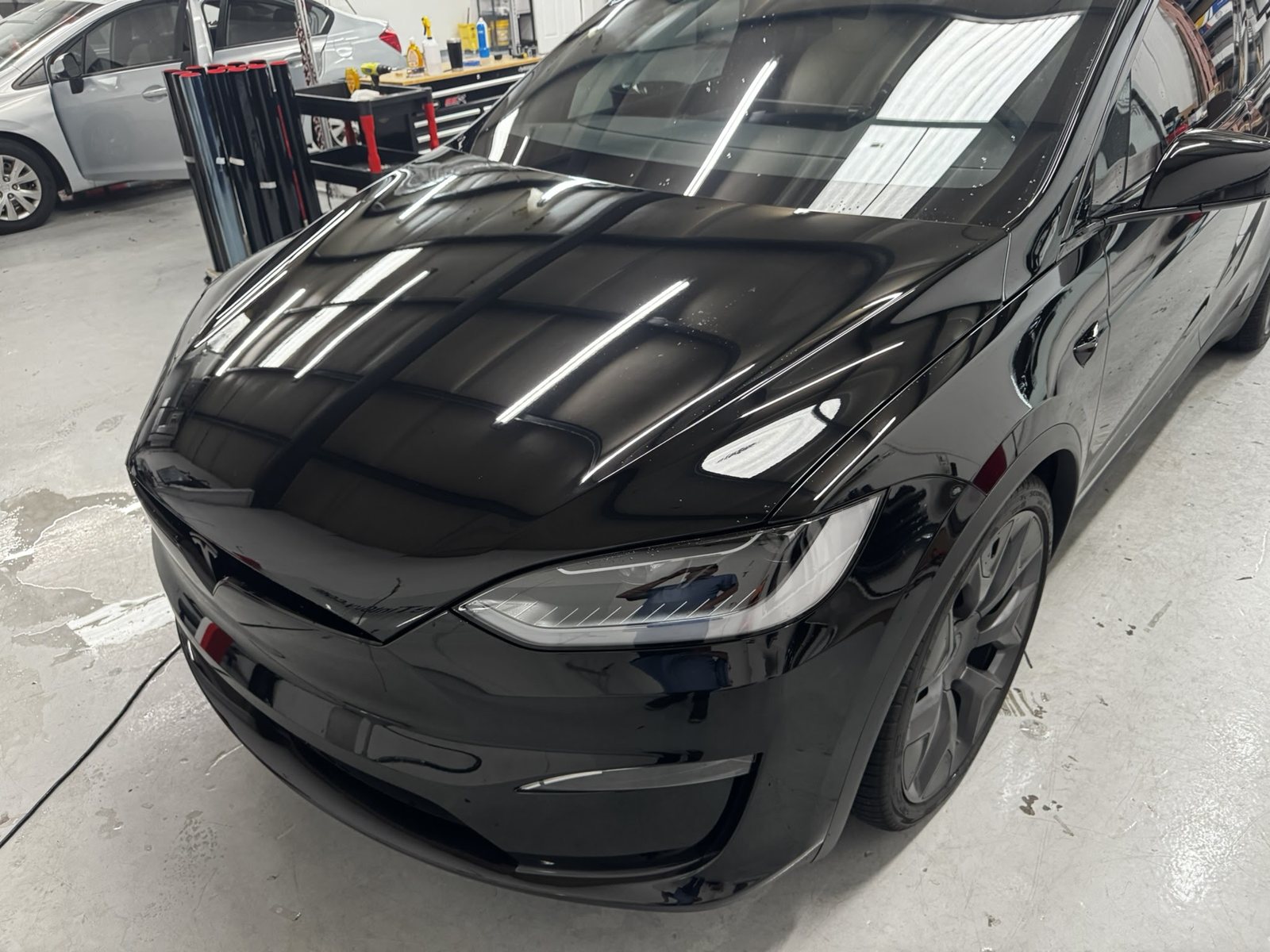 Front of a black Tesla Model X inside The Tint Guy shop