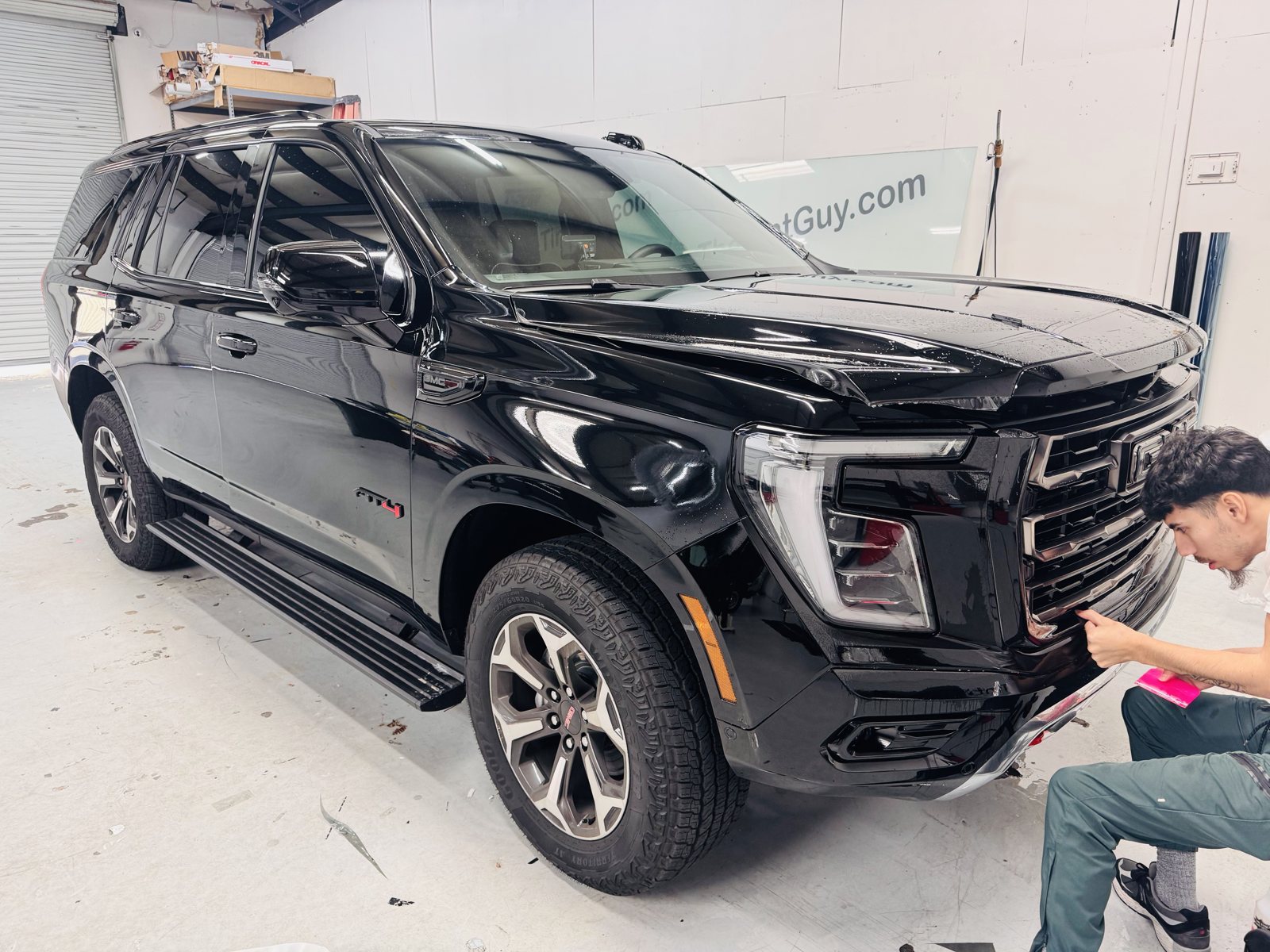 Installer working on a black GMC Yukon inside The Tint Guy shop