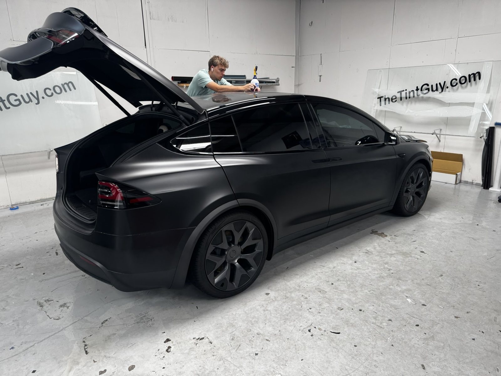 Installer working on a black Tesla Model X with the rear hatch open at The Tint Guy