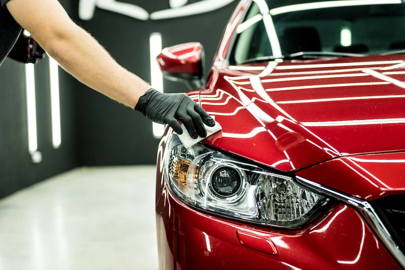 red car PPF Car service worker applying nano coating on a car detail